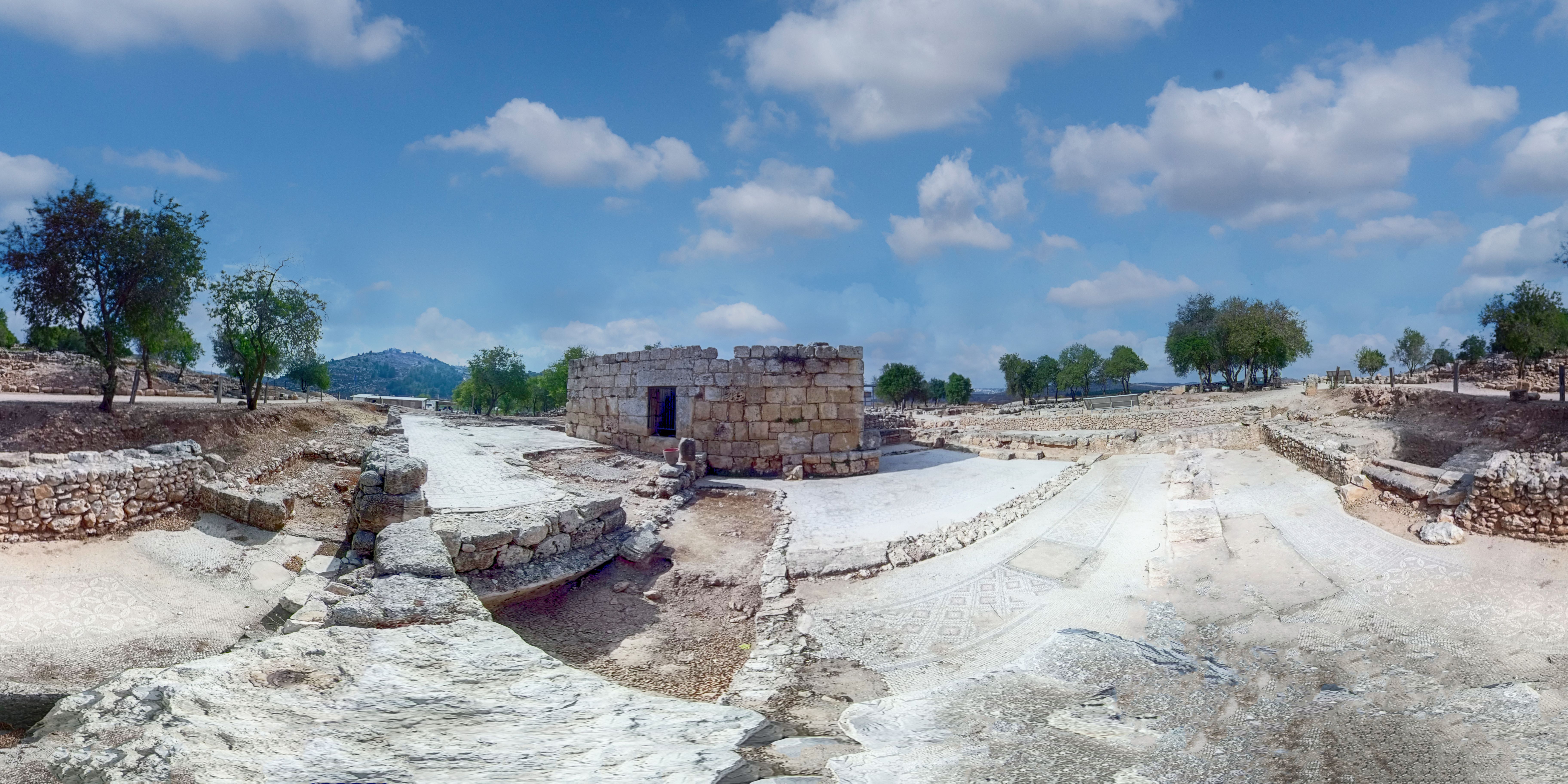 Panoramic view of the Tel Shiloh excavation site with excavated walls and a reconstructed stone structure